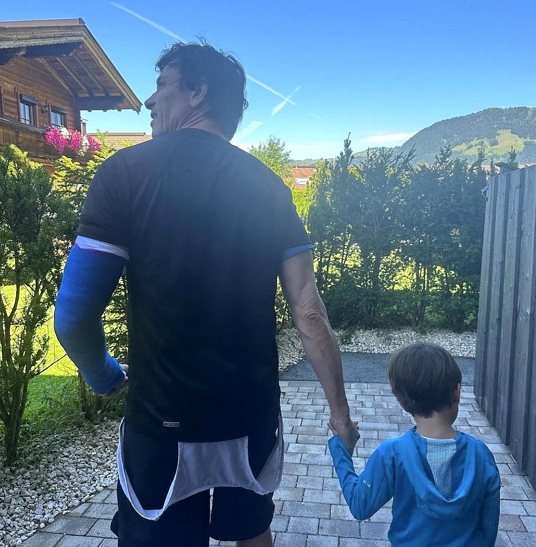 Toto Wolff walks with his son sporting a cast on his left arm