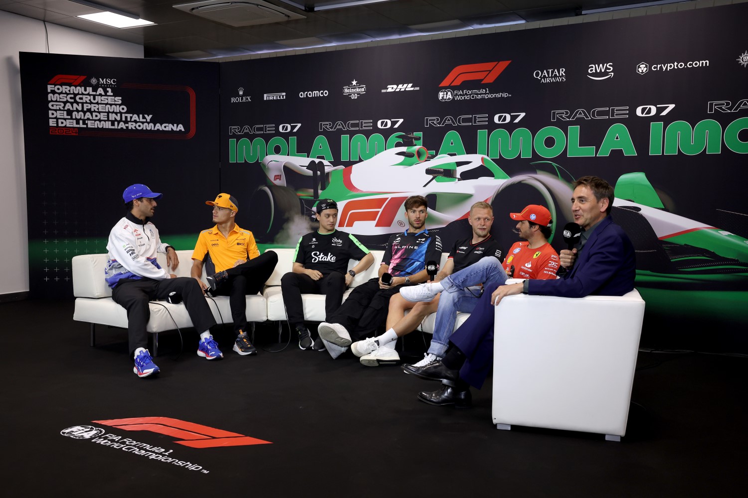 (L to R) Daniel Ricciardo of Australia and Visa Cash App RB, Lando Norris of Great Britain and McLaren, Zhou Guanyu of China and Stake F1 Team Kick Sauber, Pierre Gasly of France and Alpine F1, Kevin Magnussen of Denmark and Haas F1 and Carlos Sainz of Spain and Ferrari attend the Drivers Press Conference with Tom Clarkson during previews ahead of the F1 Grand Prix of Emilia-Romagna at Autodromo Enzo e Dino Ferrari Circuit on May 16, 2024 in Imola, Italy. (Photo by Lars Baron/Getty Images) // Getty Images / Red Bull Content Pool