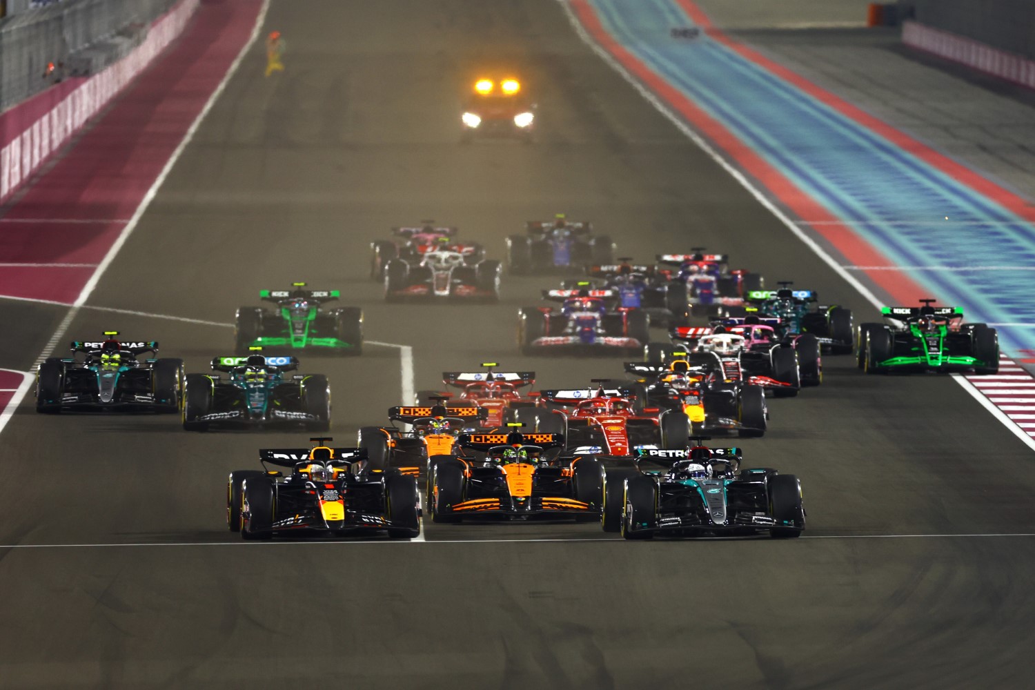 George Russell of Great Britain driving the (63) Mercedes AMG Petronas F1 Team W15 and Max Verstappen of the Netherlands driving the (1) Oracle Red Bull Racing RB20 lead the field into turn 1 at the start during the F1 Grand Prix of Qatar at Lusail International Circuit on December 01, 2024 in Lusail City, Qatar. (Photo by Mark Thompson/Getty Images) // Getty Images / Red Bull Content Pool