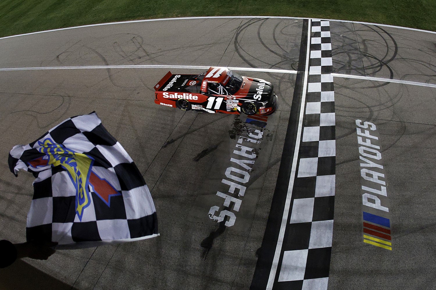 Corey Heim, driver of the #11 Safelite Toyota, takes the checkered flag to win the NASCAR Craftsman Truck Series Kubota Tractor 200 at Kansas Speedway on September 27, 2024 in Kansas City, Kansas. (Photo by Sean Gardner/Getty Images)